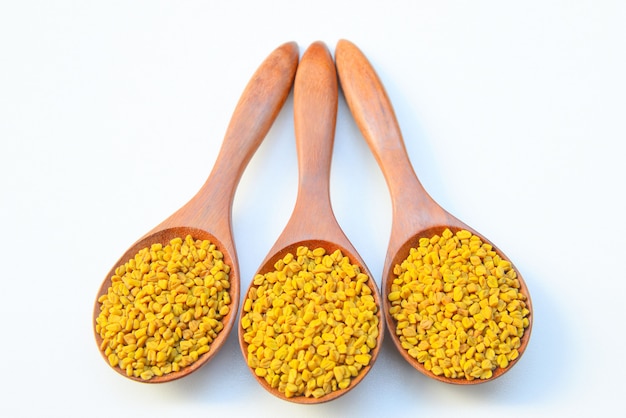 Fenugreek seeds in wooden spoon on White background