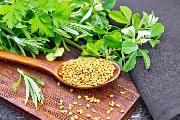 Fenugreek in spoon with herbs on black board