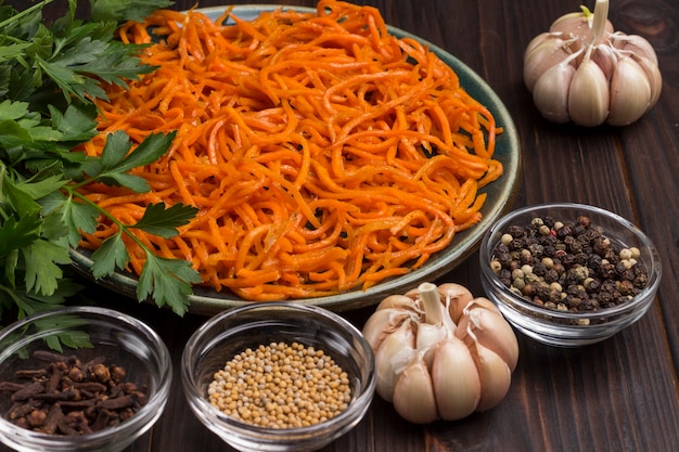 Fermented carrots in plate. Spices, garlic and parsley on table. Natural remedy for boosting immune system. Close up