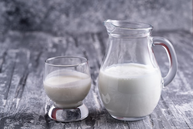 Fermented drink kefir in a glass jar and in a glass on gray table.