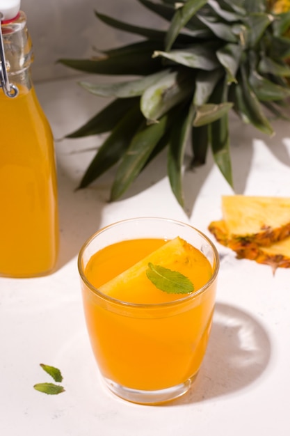 Ферментированный напиток из ананаса из чайного гриба на белой тарелке рядом с ингредиентами. Вертикальное фото