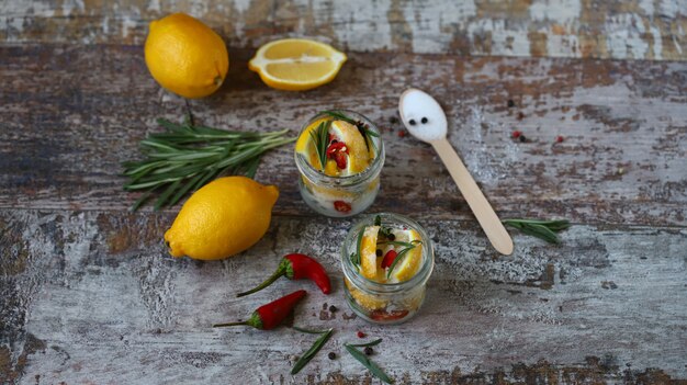 Fermented lemons in jars of salt, chili pepper and rosemary. 