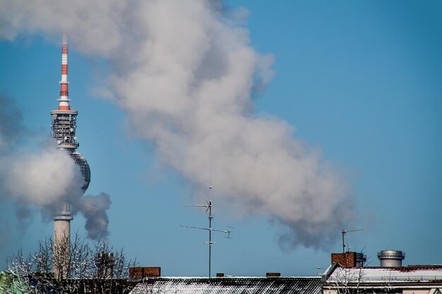 Foto torre televisiva coperta di fumo dall'industria contro un cielo blu limpido