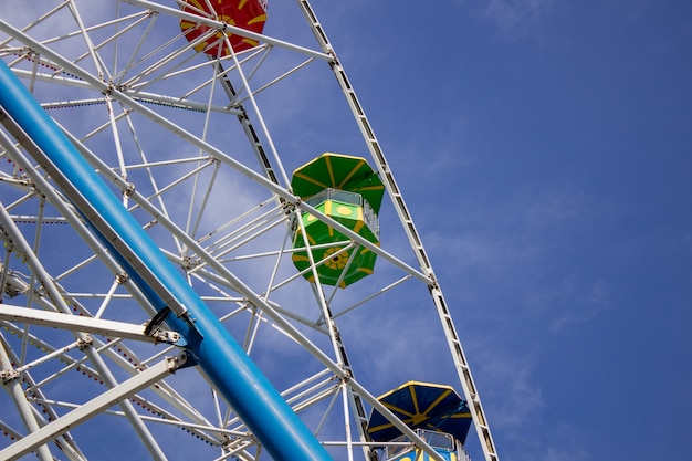 Ferris wheel against the sky. Colorful booths of the Ferris wheel. Bottom view.