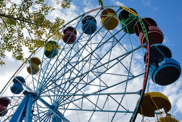 Ferris Wheel against trees and the sky with clouds