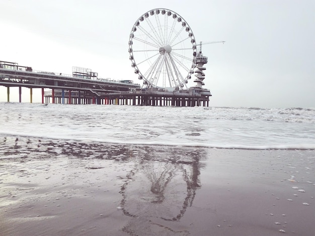 Ferris wheel at beach against clear sky