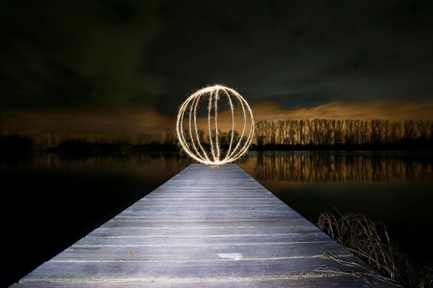 夜空に照らされた湖の横のフェリスホイール