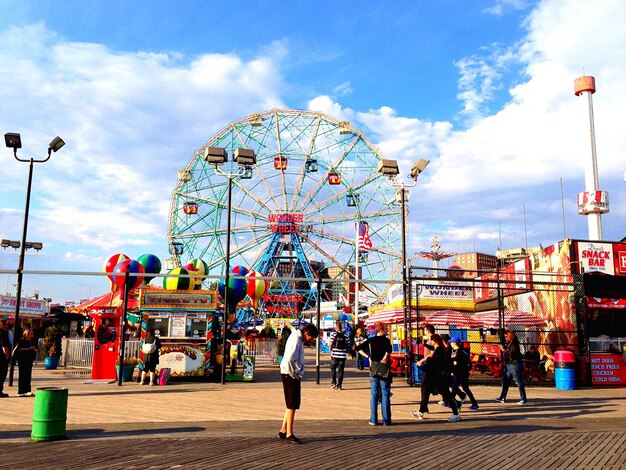 Ferris wheel at coney island against sky with boardwalk