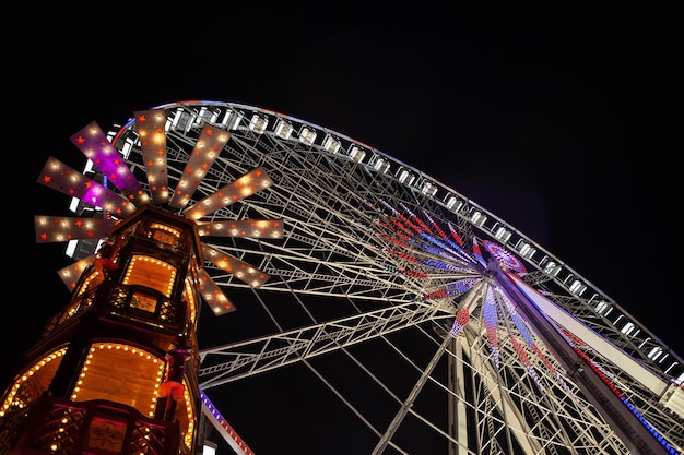 Ferris wheel and merrygoround illuminated at night