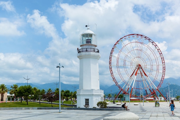 Ferris wheel and old lighthouse on the embankment in Batumi Modern buildings and tourism