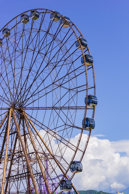 Ferris wheel in sunny summer sochi on blue cloudy sky background