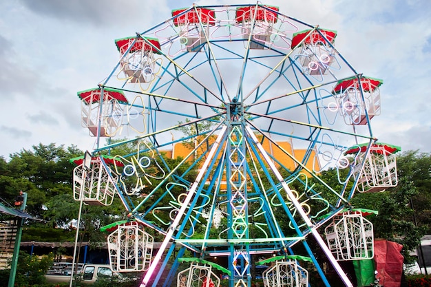 Игрушка колесо обозрения на открытом воздухе для тайских семейных людей и детей. Дети выбирают игру в карнавальном парке развлечений на уличном базаре на ежегодном храмовом фестивале в Банг Буа Тонг в Нонтхабури, Таиланд.