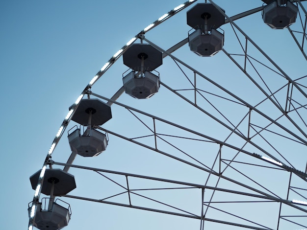 Ferris wheel with empty booths close up in amusement park on a\
clear sky summer fun for the whole family