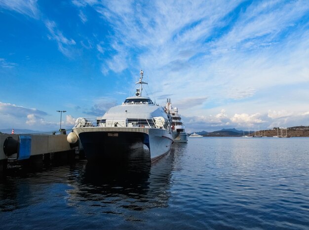 A ferry in the harbor on backdrop of picturesque coastline of Aegean Sea and blue sky with clouds