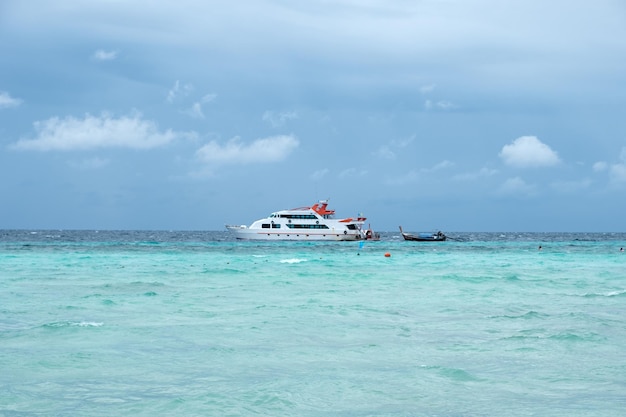 Ferry ship with wooden long tail boat on turquoise sea