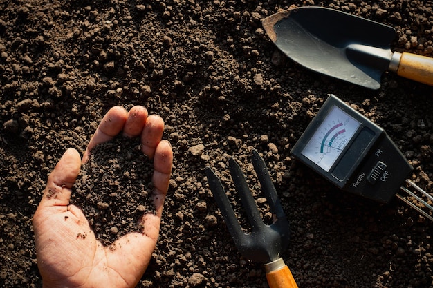 Photo the fertile loam soil was in the hands of the man and the farming equipment was placed in it.