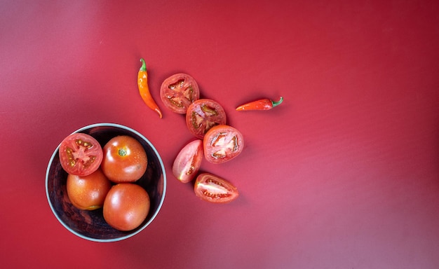 Pomodoro fesh e verdure al peperoncino isolate su sfondo rosso chiaro