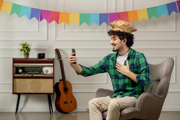 festa junina cute young guy in straw hat with retro radio and colorful flags talking on videocall