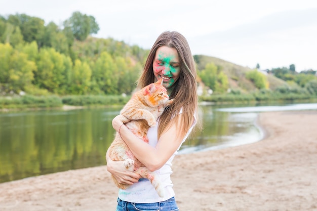 축제 holi, 휴일, 여름 관광 및 자연 개념-자연 배경에 고양이와 페인트에 젊은 매력적인 젊은 여자.