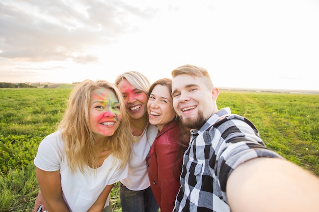 Festival e concetto di tecnologia: gruppo di amici che scattano selfie o foto di sé utilizzando il cellulare
