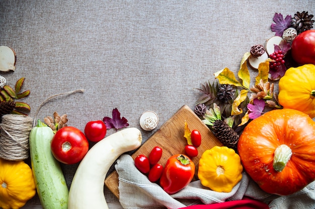 Festive autumn composition from pumpkins, leaves, tomato and squash on the beige background. Concept of Thanksgiving day or Halloween