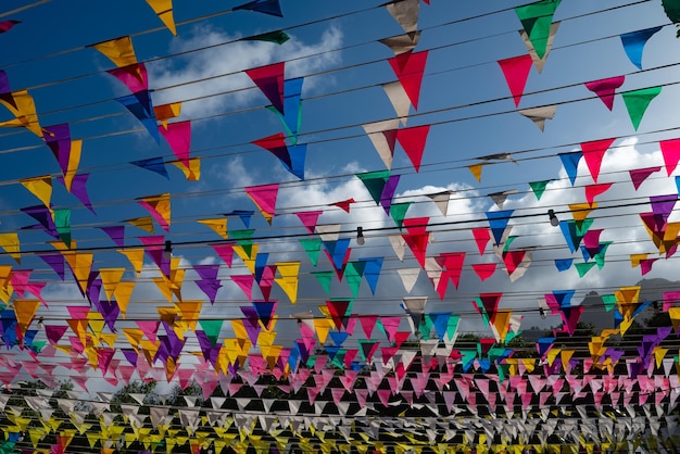 Festive background of colorful triangular flags on blue sky background Fun atmoshere of summer holiday music festival birthday celebration Red purple yellow green blue flags in stripe pattern