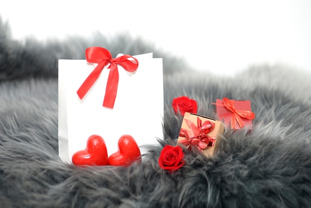 Photo festive background from gift bag with bowheartsgift boxes on gray fur for valentines daybirthday