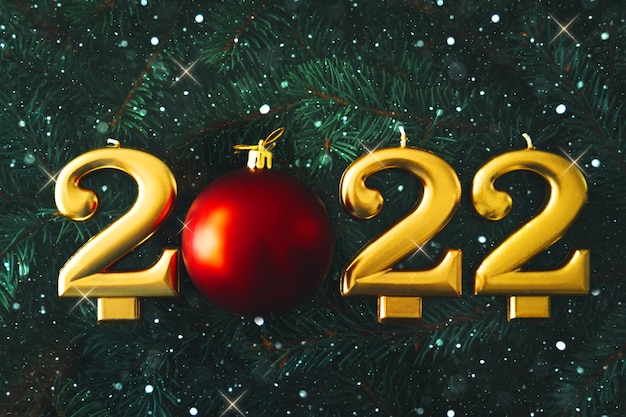 Festive background Happy New Year 2022. Gold candles on the background of fir branches. Stars and snowflakes.