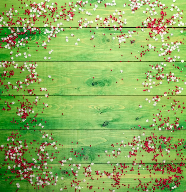 Festive background Sugar confectionery sprinkling on green boards Free space for designFlat lay