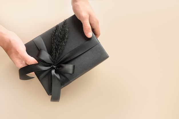 Festive black gift with decorations in hand for Father Day. Black Friday.