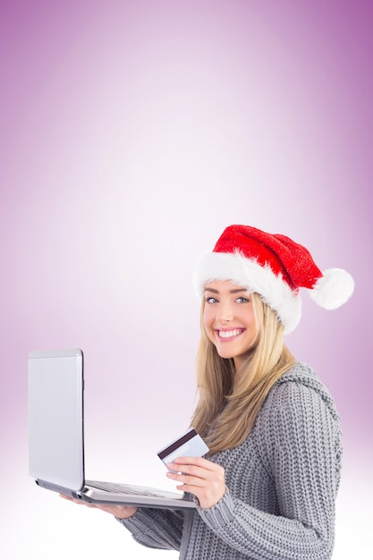 Festive blonde shopping online with laptop