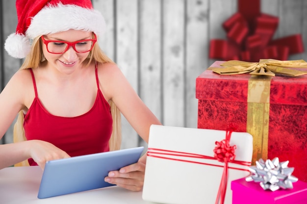 Festive blonde shopping online with tablet pc against festive bow over wood