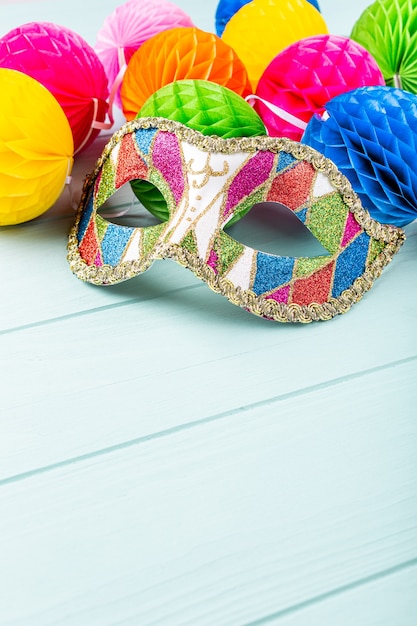 Праздничная синяя поверхность с красочной карнавальной маской и шариками из перца. Концепция поздравительной открытки для дня рождения, карнавала, вечеринки, приглашения