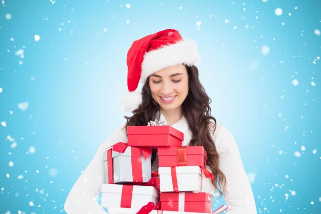 Festive brunette holding pile of gifts against blue vignette