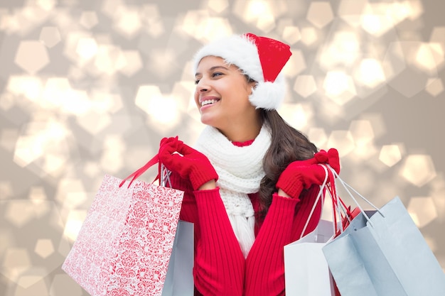 Photo festive brunette holding shopping bags against light glowing dots design pattern