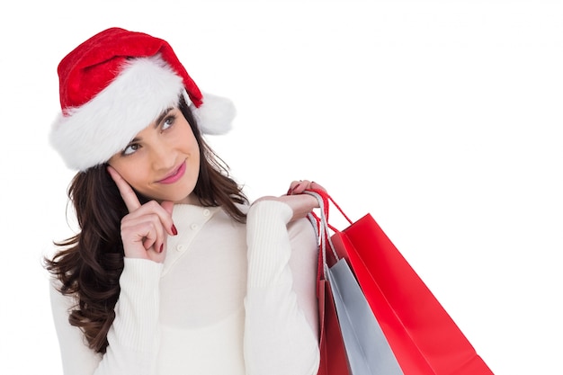 Festive brunette holding shopping bags and thinking