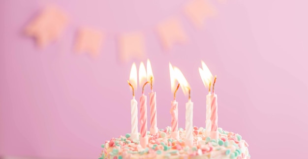 Photo festive cake with candles on the background of a festive pink wall with flags holiday concept