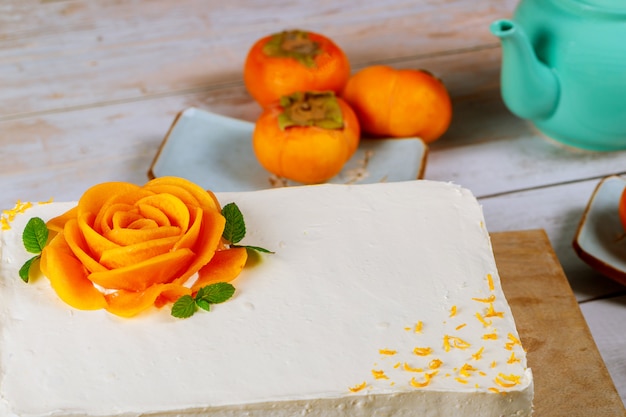 Festive cake with white whipped cream and slices of ripe persimmon