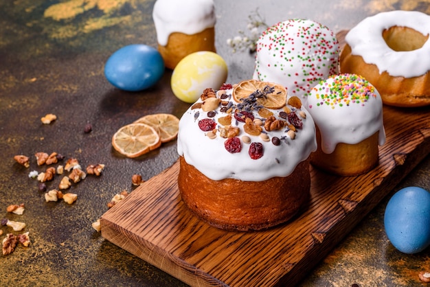 Festive cakes with white glaze, nuts and raisins with Easter eggs on the festive table. Preparations for Easter