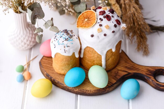 Festive cakes with white glaze, nuts and raisins with Easter eggs on the festive table