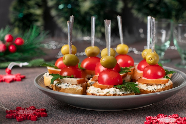 Foto canapè festivi con crouton, olive di pollo affumicato e pomodori cherry su sfondo marrone closeup