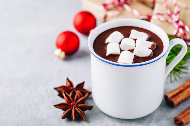 Festive Christmas Hot Chocolate with marshmallow and cinnamon stick on gray concrete stone background