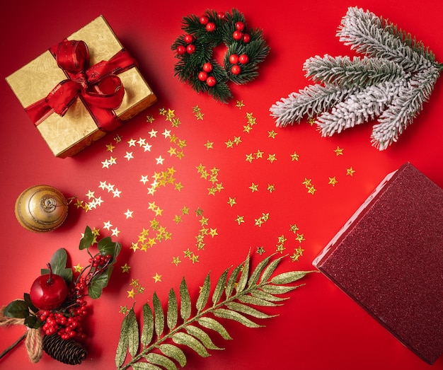 Festive Christmas and new year decorations with gift box, balls, cones and toys on red background.