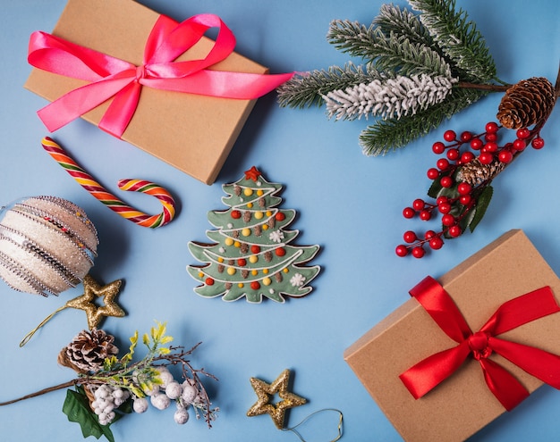 Festive Christmas and new year decorations with gift boxes and gingerbreads on blue background.