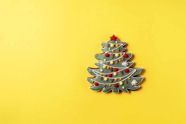 Festive Christmas and New Year gingerbread in the shape of fir tree on yellow background,copy space