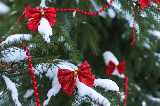 お祝いのクリスマスまたは新年のポストカード雪に覆われたトウヒの枝に赤いお祝いの弓