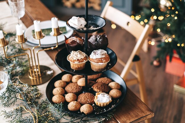 装飾が施されたキッチンで甘いクッキーとケーキが付いたお祝いのクリスマステーブル。