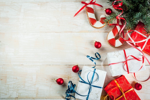 Festive Christmas wooden white background, with Christmas tree branches, pine cones, decorations, Christmas gifts and gingerbread, top view copy space