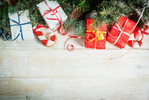 Festive Christmas wooden white background with Christmas tree branches pine cones decorations Christmas gifts and gingerbread