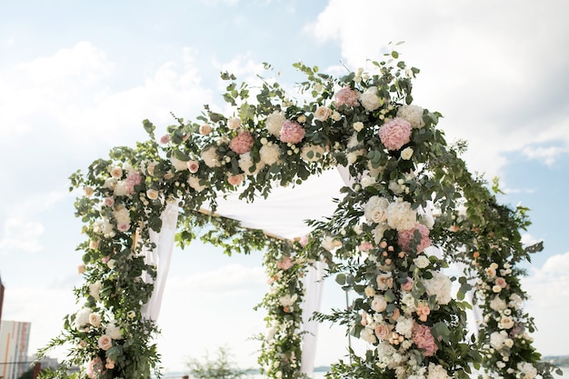 A festive chuppah decorated with fresh beautiful flowers for an outdoor wedding ceremony